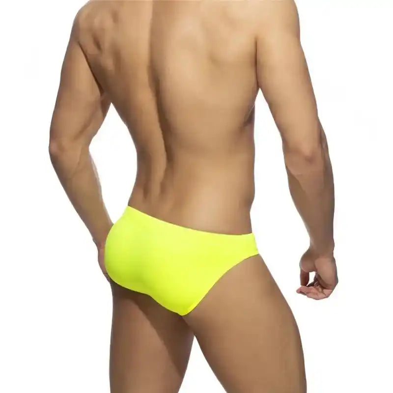 Back view of men's neon yellow swim briefs with push-up pouch and snug sunga cut, ideal for beach, surf, or poolside fashion.