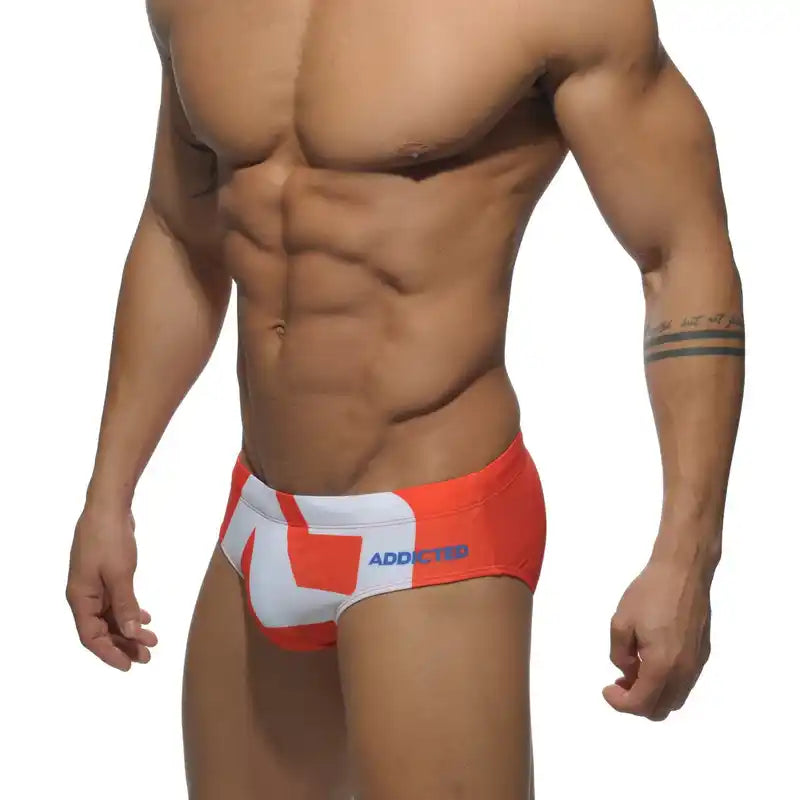 Men's low-waist swim briefs in red and white with 'ADDICTED' branding, designed for stylish beach and poolside wear.