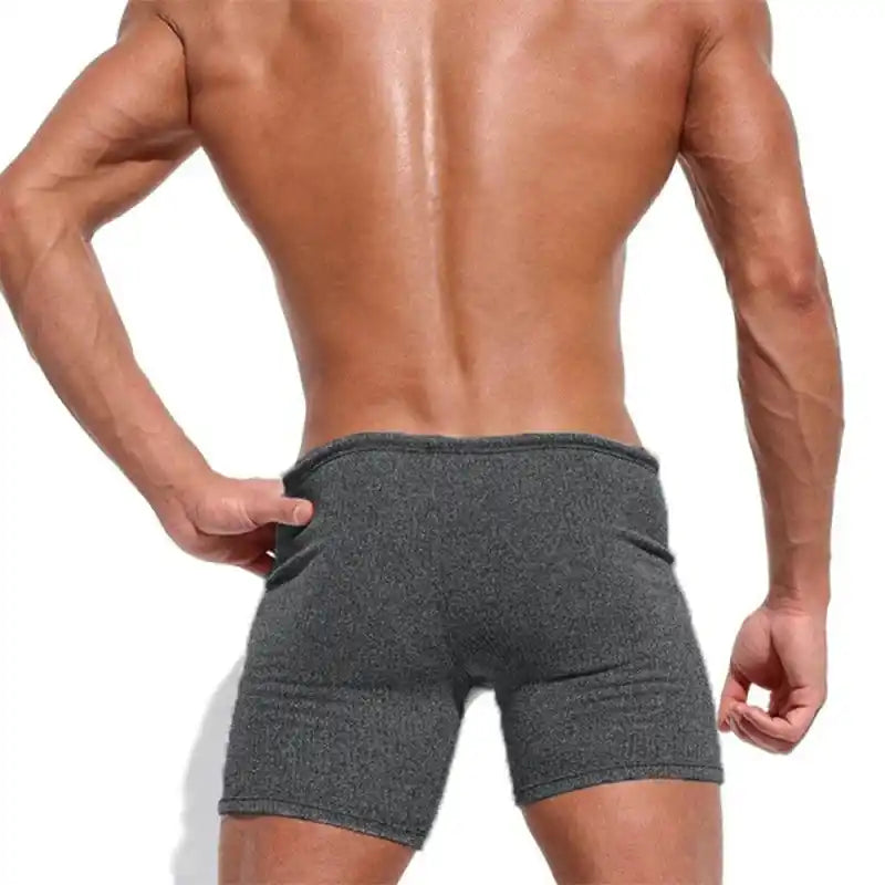 Rear view of breathable dark gray swim trunks with snug fit and quick-dry fabric. Designed for active beach or swimwear use.