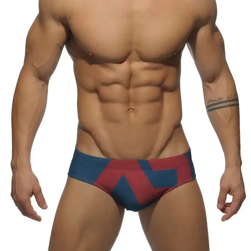 Men's low-waist swim briefs in navy and red with modern graphic pattern, ideal for pool and beach activities.