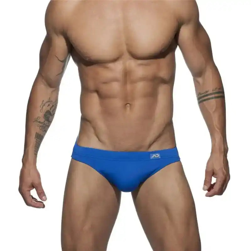 Men's neon blue swim briefs featuring a solid colour design and push-up pouch in a sleek, low-rise sunga silhouette.