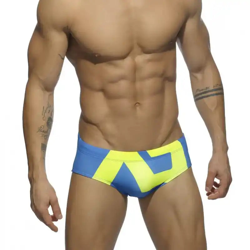 Men's low-waist swim briefs in blue and neon yellow with geometric pattern, perfect for summer swim and surfwear.