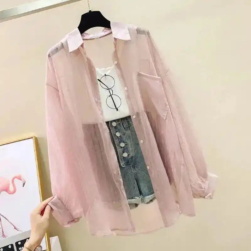 Pink sheer jacket over a white shirt and jeans on a hanger against a beige wall.