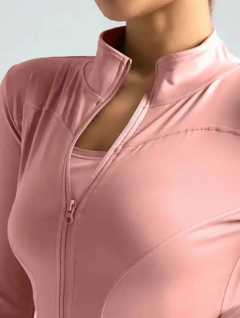Close-up of pink women's yoga jacket highlighting the smooth zipper and breathable fabric for activewear comfort.