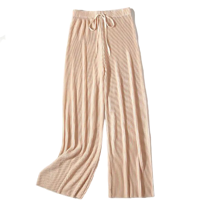 Beige pleated pants on a white surface with a photo and flowers.