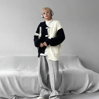 Person in layered streetwear with sweater, headphones, and silver bag