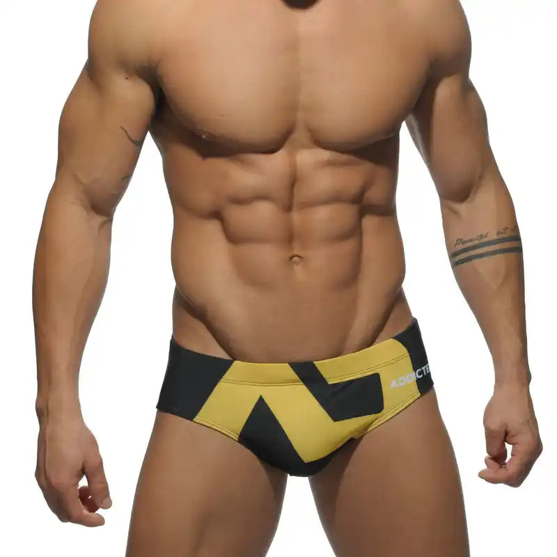 Men's low-waist swim briefs in black and yellow with 'ADDICTED' logo, designed for confident beachwear fashion.