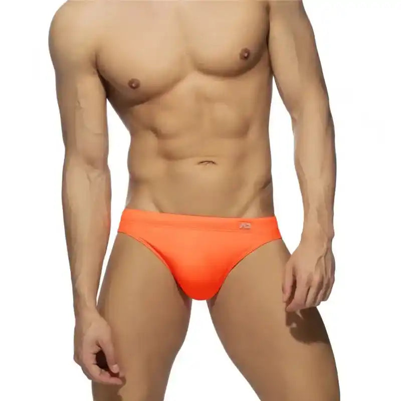 Front view of men's neon orange swim briefs with enhancing push-up pouch and solid colour sunga style for swimwear fashion.