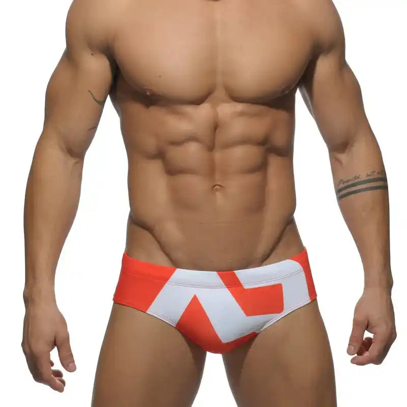 Men's low-waist swim briefs in red and white with bold geometric print, offering a sleek and sexy swimwear option.