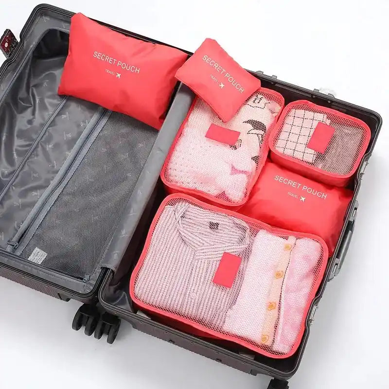 Red 6PC Travel Storage Set labeled 'Secret Pouch' used to organize sweaters and undergarments in a suitcase for travel convenience.