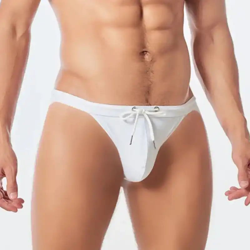 White low waist swim trunks for men featuring a big pouch and drawstring. Seamless and breathable for beach or pool use.