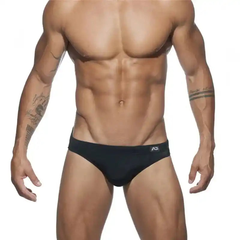 Men's black swim briefs with low-rise sunga cut and push-up pouch, designed for bold beach and poolside swimwear style.