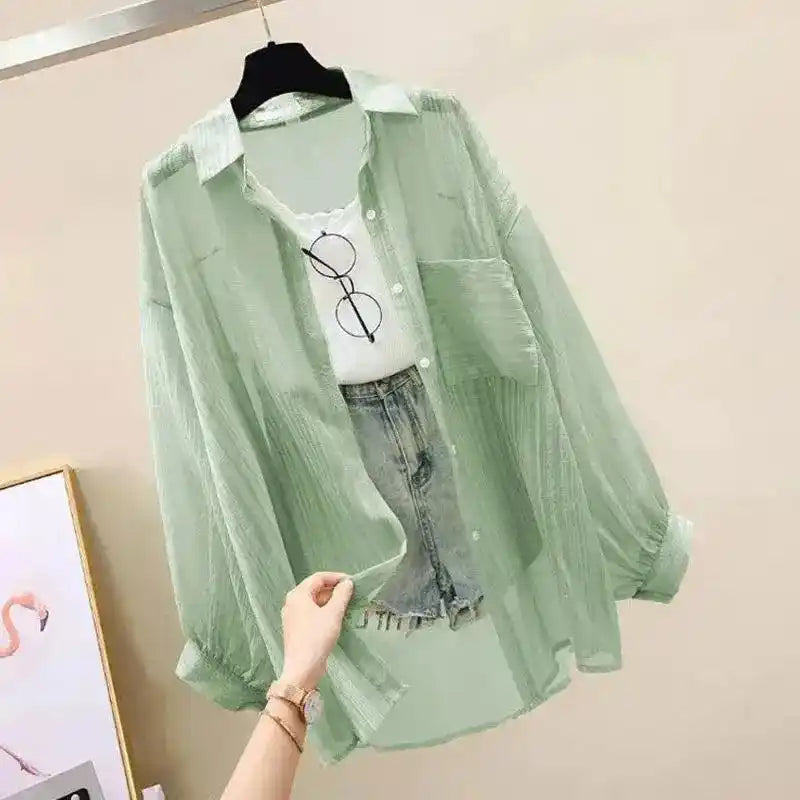 Light green sheer blouse on a hanger with a white shirt and jeans underneath.